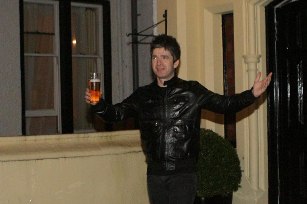noel-gallagher-holding-a-pint-of-tennents-lager-while-standi.jpg